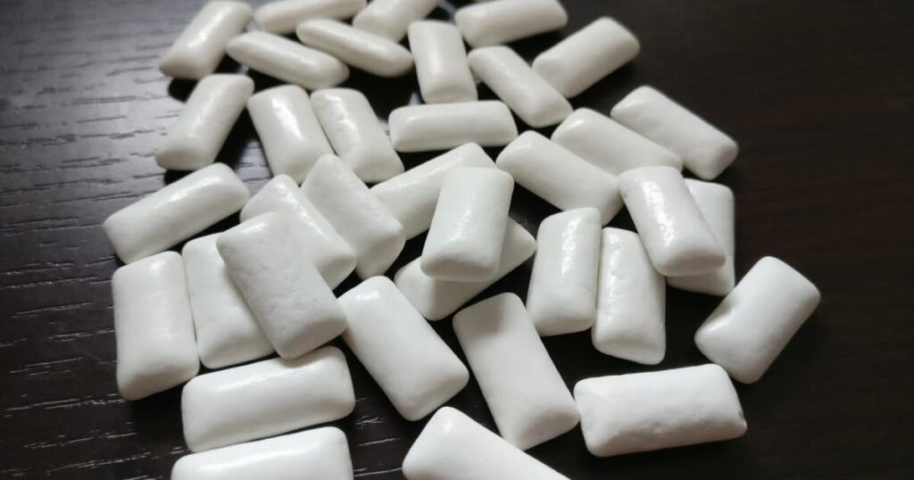 A pile of white plastic toothpaste tubes, highlighting the dangers of sugar and xylitol for dogs in dental care products.